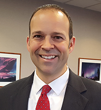 Man wearing suit and smiling while standing in meeting room