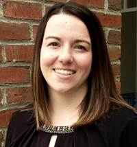 Professional women standing in front of a brick wall smiling