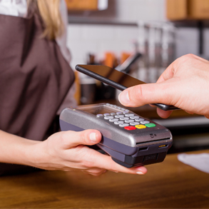 Hand of man holding phone over card reader to pay for purchase with Wallet Pay app.