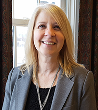 Smiling professional woman with long blond hair and grey suit.