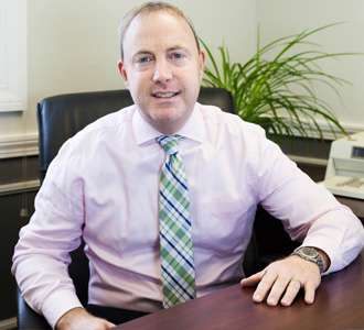 Professional man smiling, sitting at his desk.