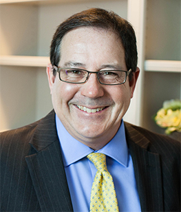 Professional man with dark hair and glasses, nice smile, dark suit.