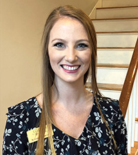 Smiling young professional woman in flowery blouse.